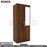 A wooden legacy cupboard with open doors showing clothes hanging inside, placed in a room with a chair and decorative wall art.